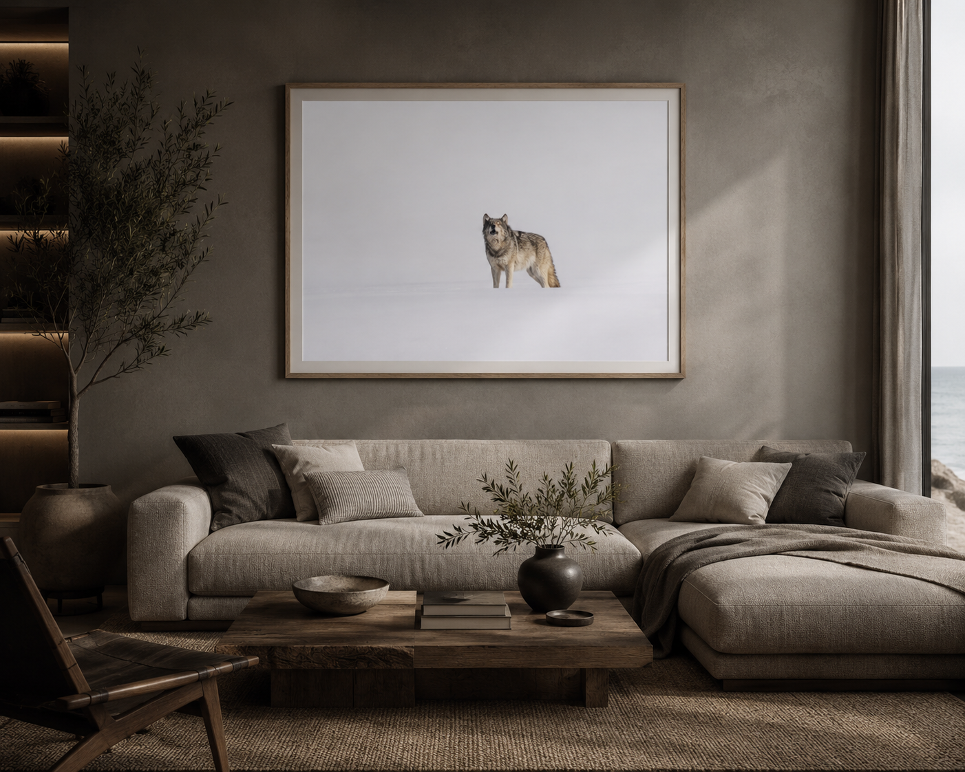 Framed print of a wolf mid-howl in soft snow light, hung above a taupe sectional in a moody, warm-lit living room